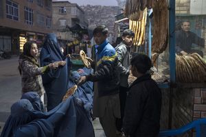 Un hombre distribuye pan a mujeres afganas que llevan burka fuera de una panadería en Kabul, Afganistán, el jueves 2 de diciembre de 2021. Según cifras de la ONU de principios de noviembre, casi 24 millones de personas en Afganistán, alrededor del 60% de la población, sufren del hambre aguda, incluidos 8,7 millones que viven cerca de la hambruna. Un número cada vez mayor de niños desnutridos ha llenado las salas de los hospitales. Foto AP / Petros Giannakouris