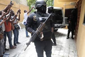 Police stand guard as journalists take photos of Colombian suspects who were brought in a van to appear before the investigating judge appointed to the case of the assassination of late Haitian President Jovenel Moise in Port-au-Prince, Haiti, Tuesday, Aug. 29, 2023. Moise was assassinated on July 7, 2021, when he was shot a dozen times at his private home in an attack that also seriously injured his wife. (AP Photo/Odelyn Joseph)