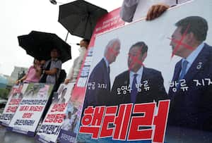 Un manifestante sostiene una pancarta que muestra una imagen del presidente estadounidense Joe Biden (izquierda), el primer ministro japonés Fumio Kishida y el presidente surcoreano Yoon Suk Yeol (derecha) durante una manifestación para oponerse a los ejercicios militares conjuntos entre Estados Unidos y Corea del Sur, cerca de la Embajada de Estados Unidos en Seúl, Corea del Sur, martes 29 de agosto de 2023. (Foto AP/Ahn Young-joon)