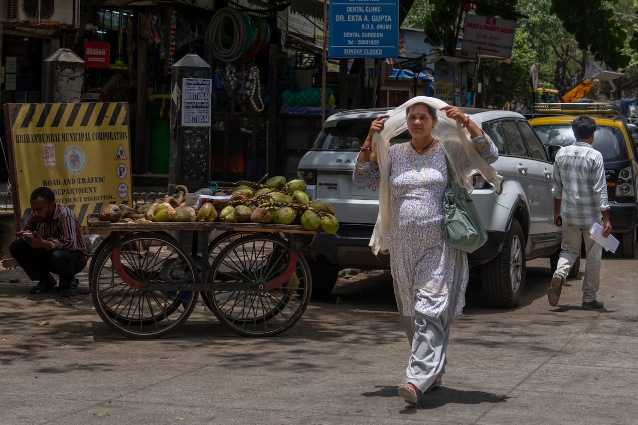 Una mujer se cubre la cabeza con un pañuelo para protegerse del calor mientras camina en un caluroso día de verano en Mumbai, India, el jueves 30 de mayo de 2024.