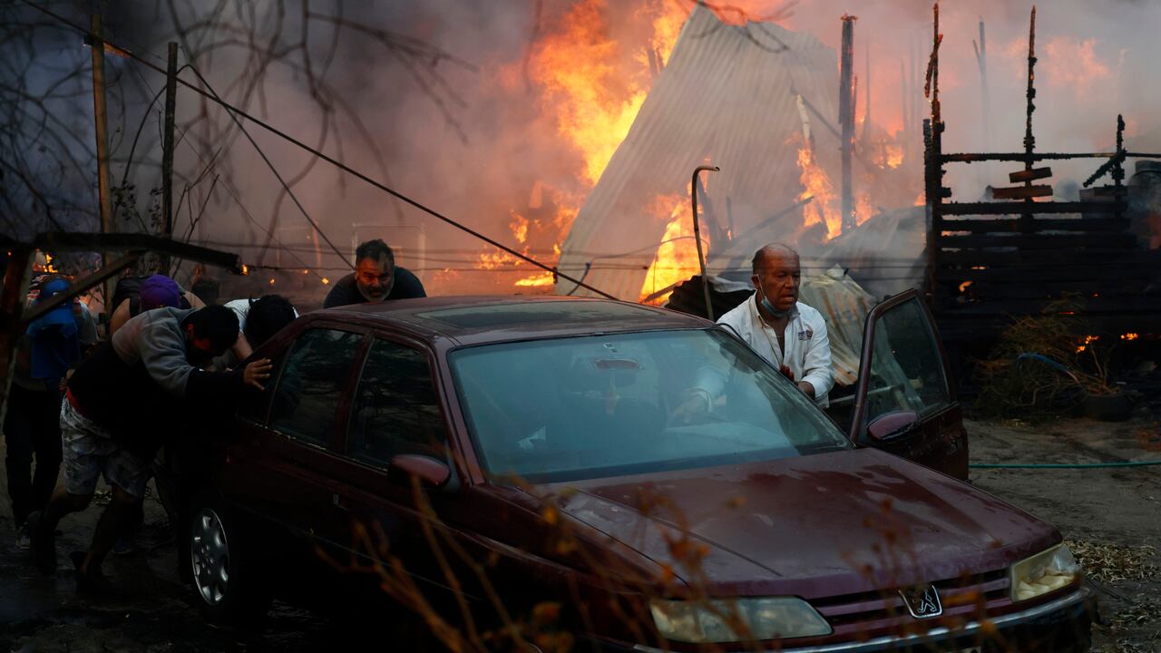 Residentes empujan un automóvil para alejarse de un incendio forestal que arrasa casas en Villa Alemana, Valparaíso, Chile, el viernes 2 de febrero de 2024.