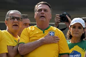 El ex presidente brasileño Jair Bolsonaro (C) canta el himno nacional junto a su esposa Michelle Bolsonaro (R) y el pastor Silas Malafaia (L) durante una manifestación en Sao Paulo, Brasil, el 25 de febrero de 2024.