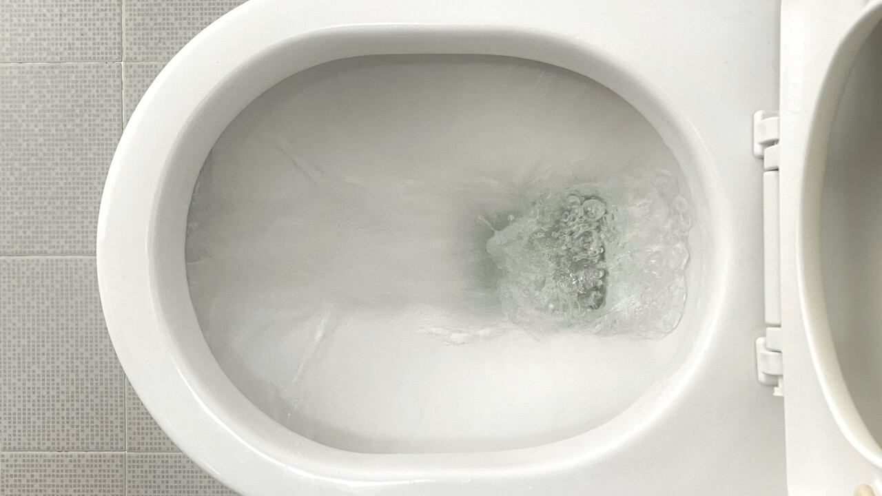 Overhead view of water flushing through a white color toilet bowl