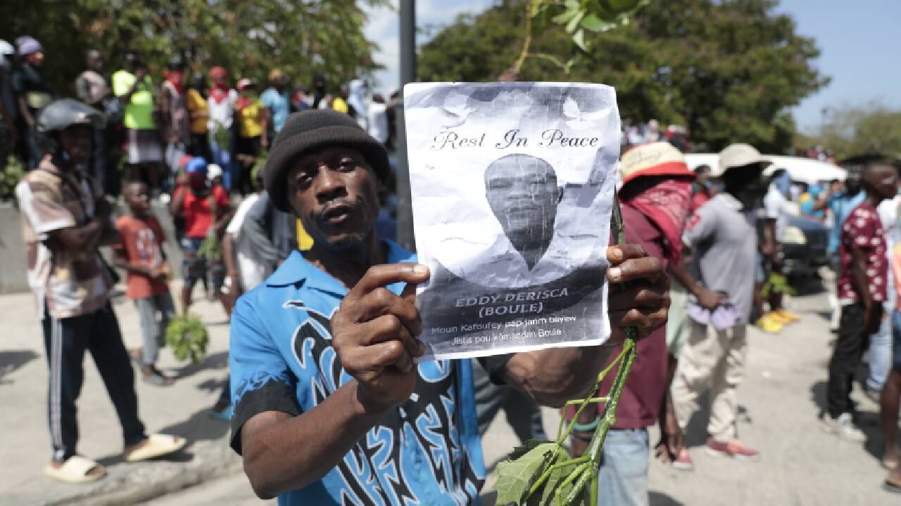 Un manifestante sostiene una foto del oficial de policía, Eddy Derisca, quien murió en la violencia de pandillas, durante una protesta contra la inseguridad en Haití, el lunes 7 de agosto de 2023.