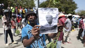 Un manifestante sostiene una foto del oficial de policía, Eddy Derisca, quien murió en la violencia de pandillas, durante una protesta contra la inseguridad en Haití, el lunes 7 de agosto de 2023.