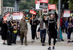 FILE - Picketers pass near a studio entrance during a Writers Guild rally outside Warner Bros. Studios, Wednesday, May 24, 2023, in Burbank, Calif. As a strike drags on, about 1,000 Hollywood writers and their supporters have marched and rallied in Los Angeles for a new contract with studios that includes the payment guarantees and job security they say they deserve. Speakers at Wednesday's event on June 21, emphasized the solidarity the Writers Guild of America has received from other unions. (AP Photo/Richard Vogel, File)