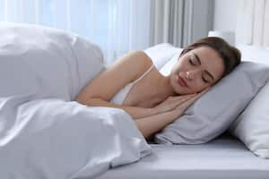 Young woman sleeping in comfortable bed with silky linens