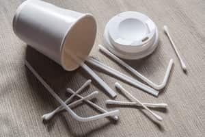 Single-use items concept. Coffee cup, lids, stirrers and cotton buds.