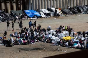 Migrantes se reúnen entre las cercas primaria y secundaria de la frontera entre Estados Unidos y México antes del levantamiento del Título 42, visto desde Tijuana, México, 11 de mayo de 2023. 