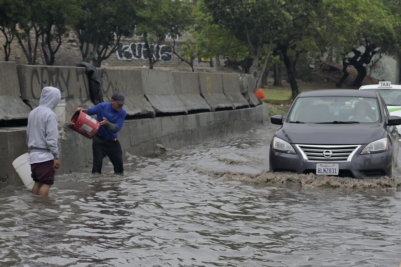 La gente intenta vaciar una calle inundada tras el paso de la tormenta tropical Hilary, que no afecta gravemente a la región a diferencia de otros lugares, en Tijuana, México, el 21 de agosto de 2023.