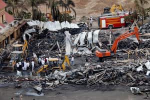 Los funcionarios limpian restos carbonizados en el lugar de un accidente de incendio al día siguiente del desastre, en un parque de diversiones en Rajkot, en el estado indio de Gujarat, el 26 de mayo de 2024.