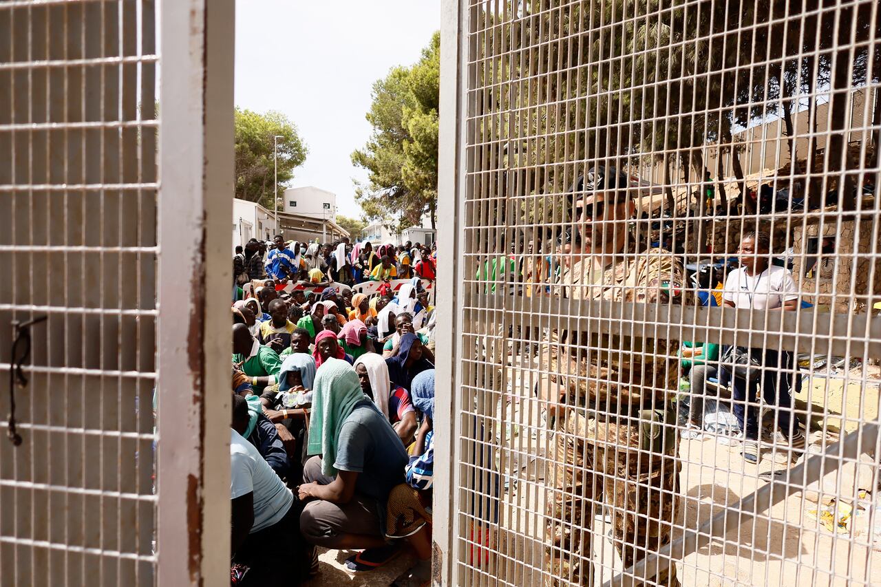 Un oficial del ejército cierra la puerta de un migrante en un centro de recepción mientras los migrantes se sientan adentro, en la isla siciliana de Lampedusa, en el sur de Italia, el sábado 16 de septiembre de 2023. Miles de migrantes y refugiados han llegado a la isla italiana de Lampedusa este una semana después de cruzar el mar Mediterráneo en pequeñas embarcaciones no aptas para navegar desde Túnez, abrumando a las autoridades locales y a las organizaciones de ayuda. (Cecilia Fabiano/LaPresse vía AP)