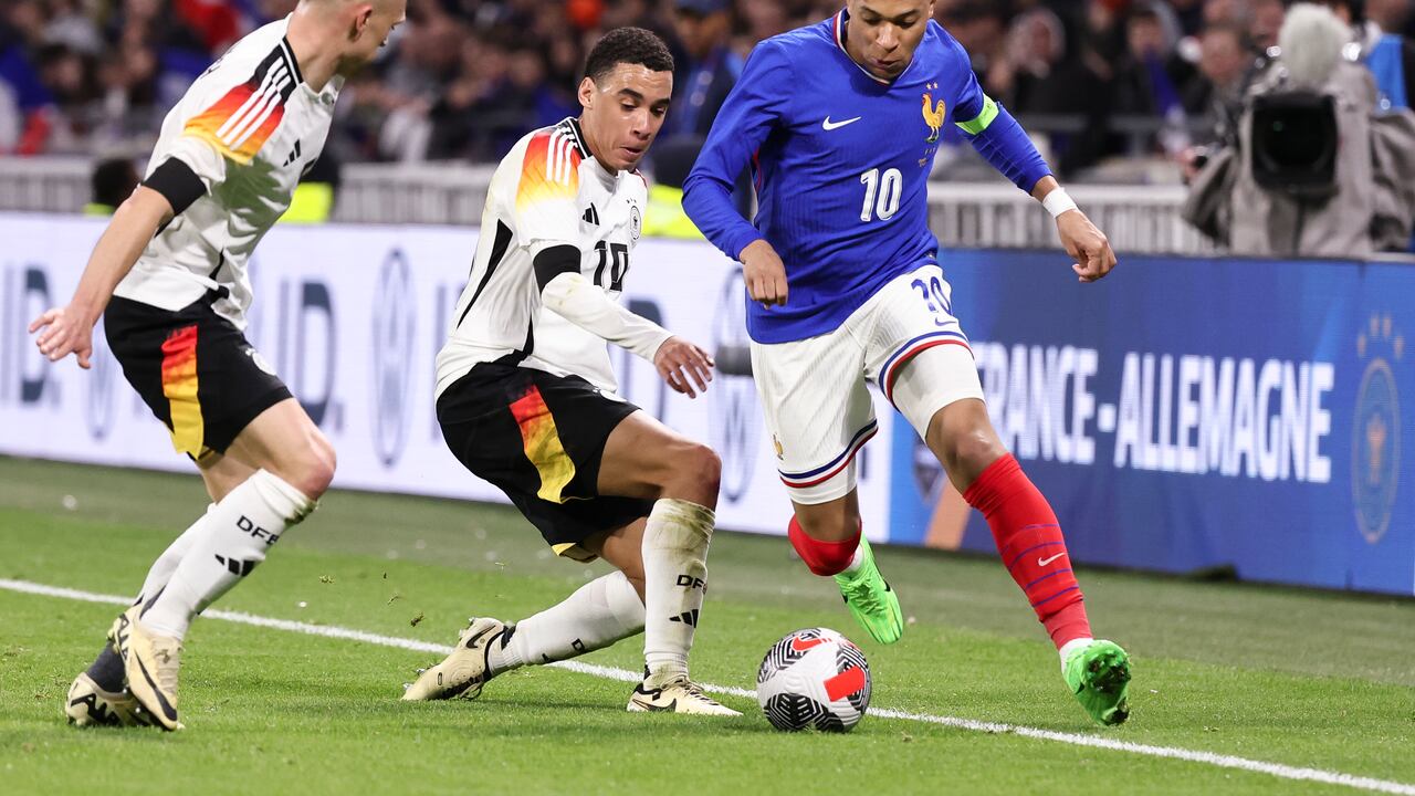 LYON, FRANCE - MARCH 23: Joshua Kimmich #6 of Germany and Jamal Musiala #10 of Germany challenge Kylian Mbappe #10 of France during the international friendly match between France and Germany at Groupama Stadium on March 23, 2024 in Lyon, France.(Photo by Catherine Steenkeste/Getty Images)