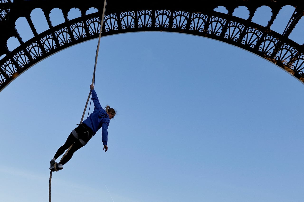 El atleta francés Anouk Garnier calienta antes de subir la cuerda a la Torre Eiffel para batir el récord mundial, en la Torre Eiffel de París