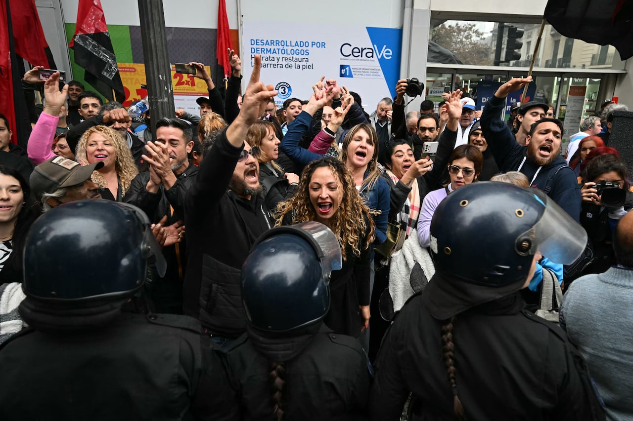 Los manifestantes gritan consignas mientras los agentes de policía hacen guardia frente al Congreso Nacional en Buenos Aires el 12 de junio de 2024. Los senadores argentinos están discutiendo un paquete de reformas clave para el presidente de extrema derecha Javier Milei, en una sesión marcada por huelgas y manifestaciones en frente al Congreso.