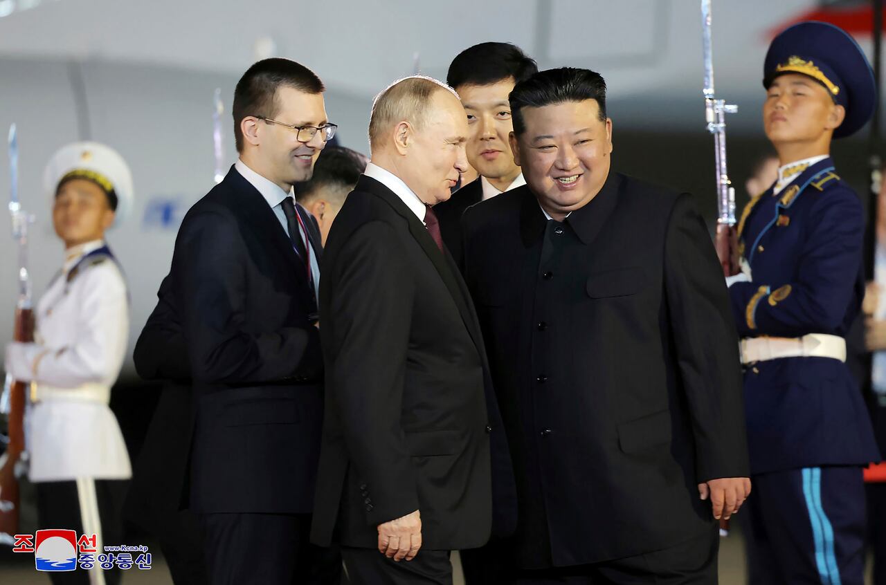 En esta fotografía proporcionada el miércoles 19 de junio de 2024 por el gobierno de Corea del Norte, el presidente ruso Vladimir Putin (centro) conversa con el líder de Corea del Norte, Kim Jong Un (centro derecha), a la llegada de Putin al Aeropuerto Internacional de Pyongyang en Pyongyang