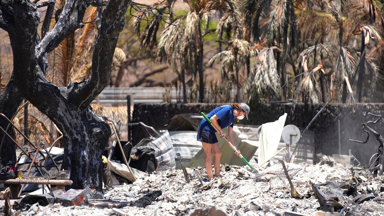 Una mujer excava entre los escombros de una casa destruida por el incendio forestal