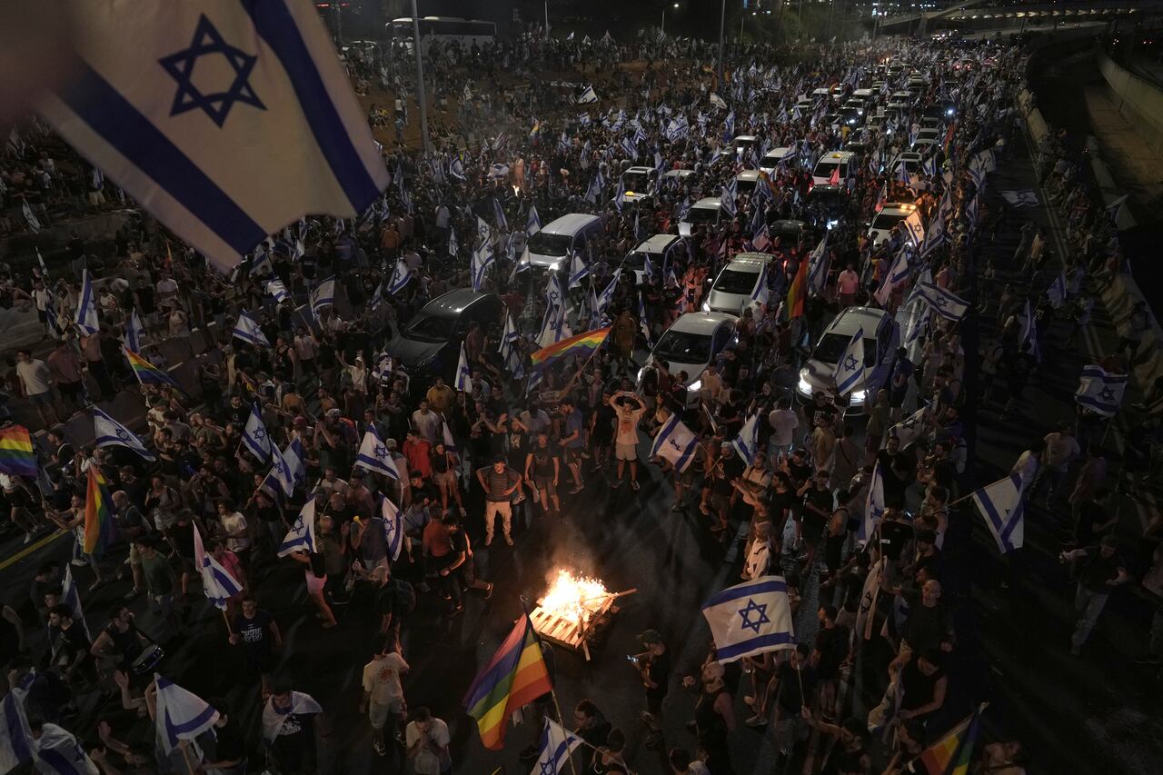 Los manifestantes encendieron un fuego mientras bloqueaban el tráfico en una carretera que cruza la ciudad durante una protesta contra los planes del gobierno de Netanyahu para reformar el sistema judicial, en Tel Aviv, el lunes 24 de julio de 2023.