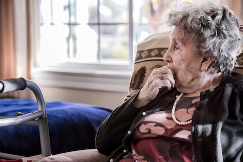 Retrato de una anciana sentada sola en un centro de atención para personas mayores