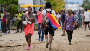 A migrant wears a Venezuelan flag in Necocli, Colombia, a stopping point for migrants taking boats to Acandi which leads to the Darien Gap, Thursday, Oct. 13, 2022. Some Venezuelans are reconsidering their journey to the U.S. after the U.S. government announced on Oct. 12 that Venezuelans who walk or swim across the border will be immediately returned to Mexico without rights to seek asylum. (AP Photo/Fernando Vergara)