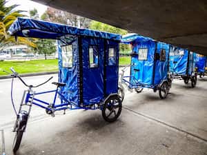Triciclos azules junto a un puente peatonal en la calle en Bogotá Colombia bicitaxi