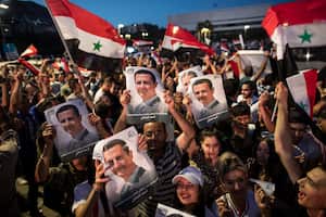 Los partidarios del presidente sirio Bashar Assad sostienen banderas nacionales e imágenes de Assad mientras celebran en la Plaza Omayyad, en Damasco, Siria, el jueves 27 de mayo de 2021 (AP Photo / Hassan Ammar).