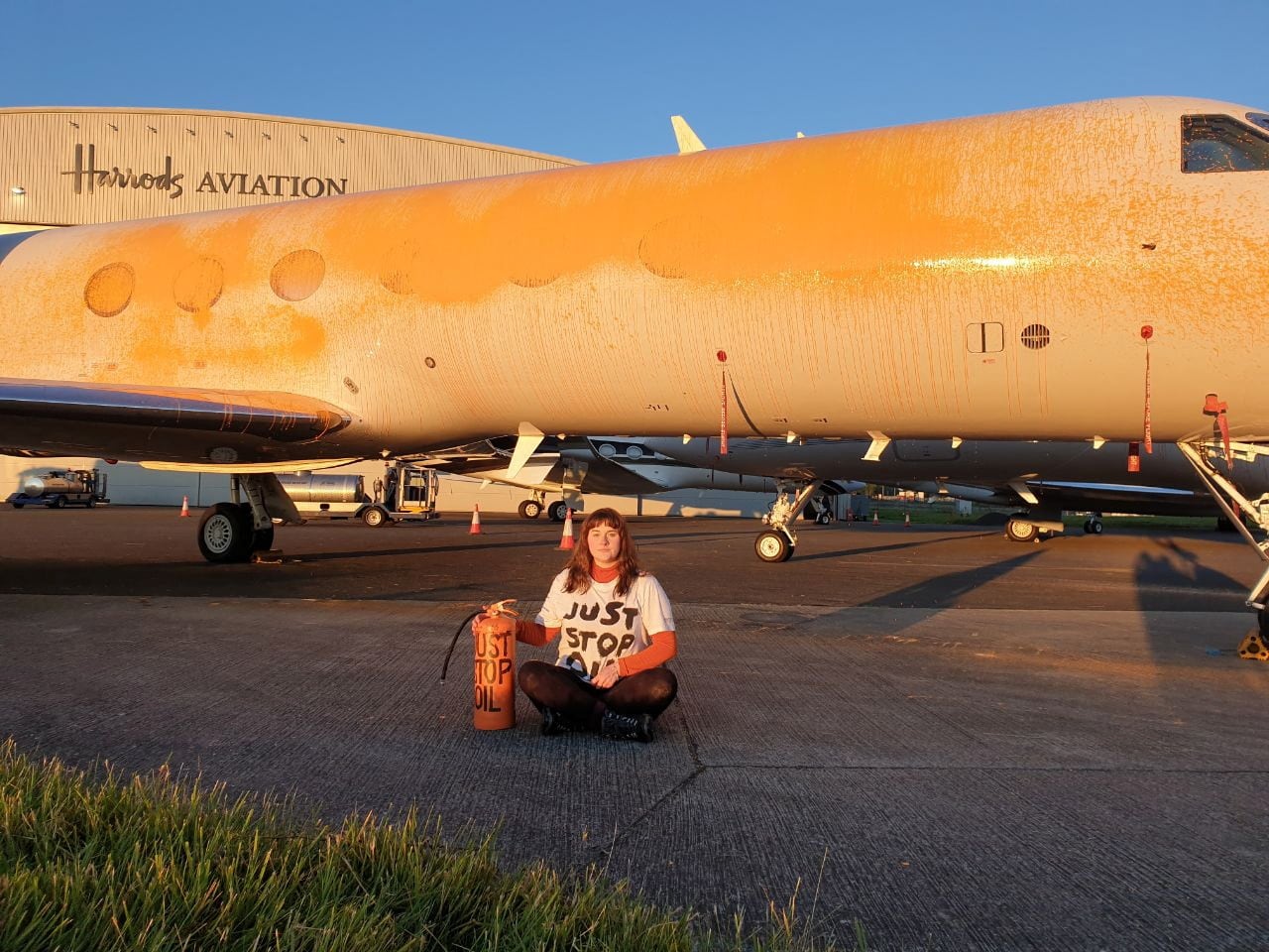 Un manifestante se sienta frente a un avión mientras miembros de Just Stop Oil pintan aviones en el aeropuerto de Stansted, Gran Bretaña, el 20 de junio de 2024.