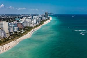 Vista aérea del paisaje urbano de South Beach Miami Florida con edificios a lo largo de la playa en un hermoso día soleado, gente en la playa y el océano