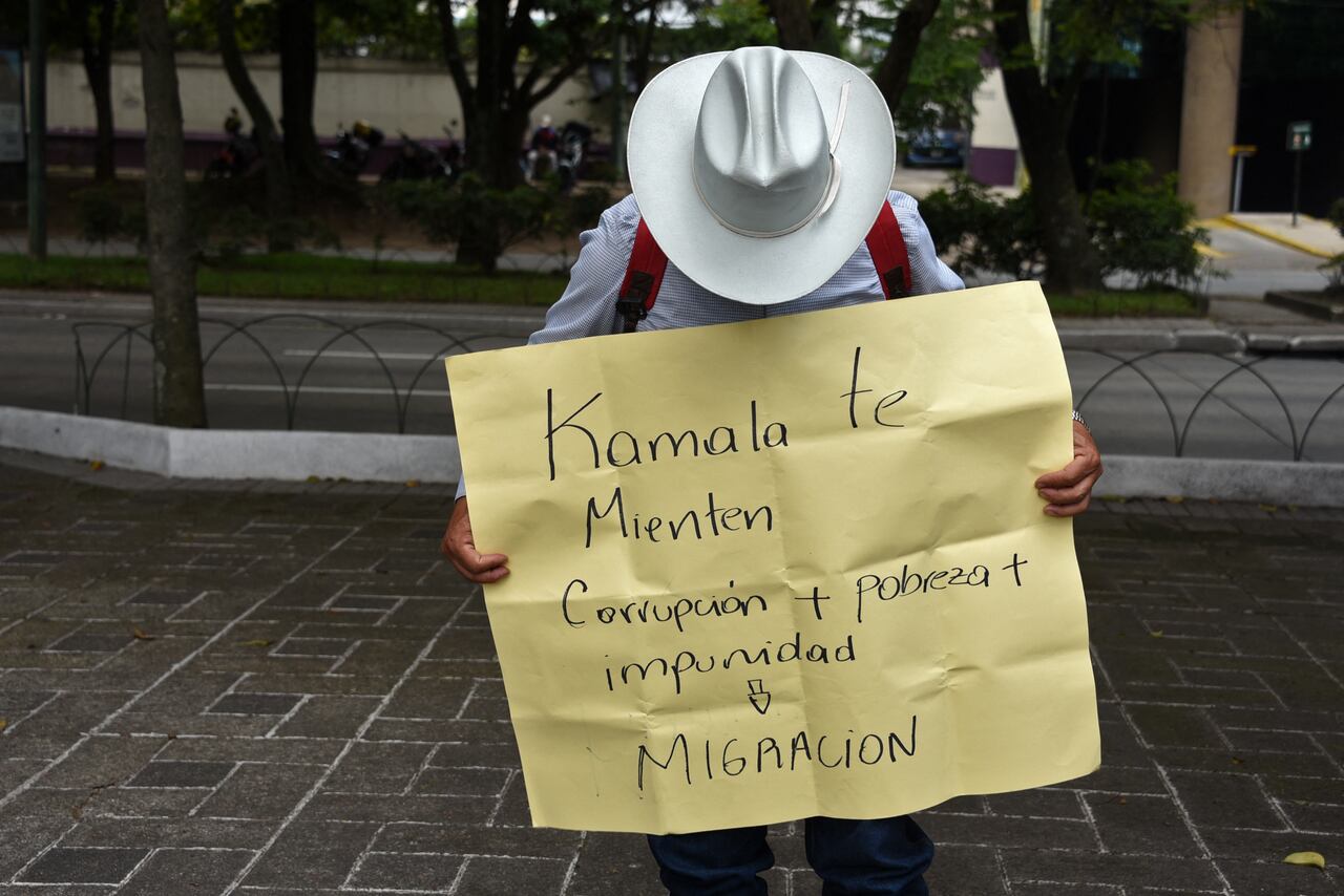 Un hombre sostiene un cartel que dice: "Kamala, te están mintiendo. Corrupción + pobreza + impunidad = Migración",  mientras participa en una protesta contra el gobierno del presidente guatemalteco Alejandro Giammattei durante la visita de la vicepresidenta de los Estados Unidos, Kamala Harris, frente a la embajada de los Estados Unidos en la ciudad de Guatemala el 7 de junio de 2021.