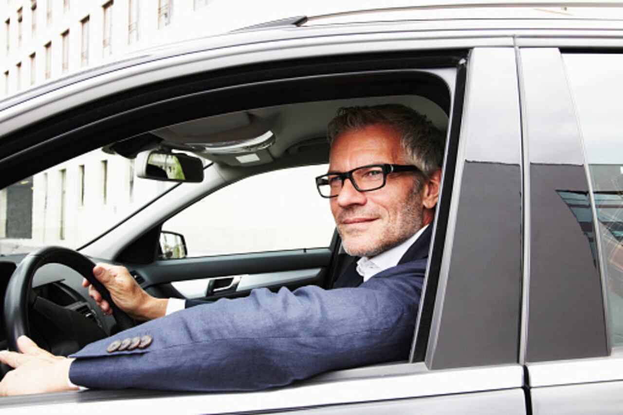 Hombre con gafas manejando un carro.