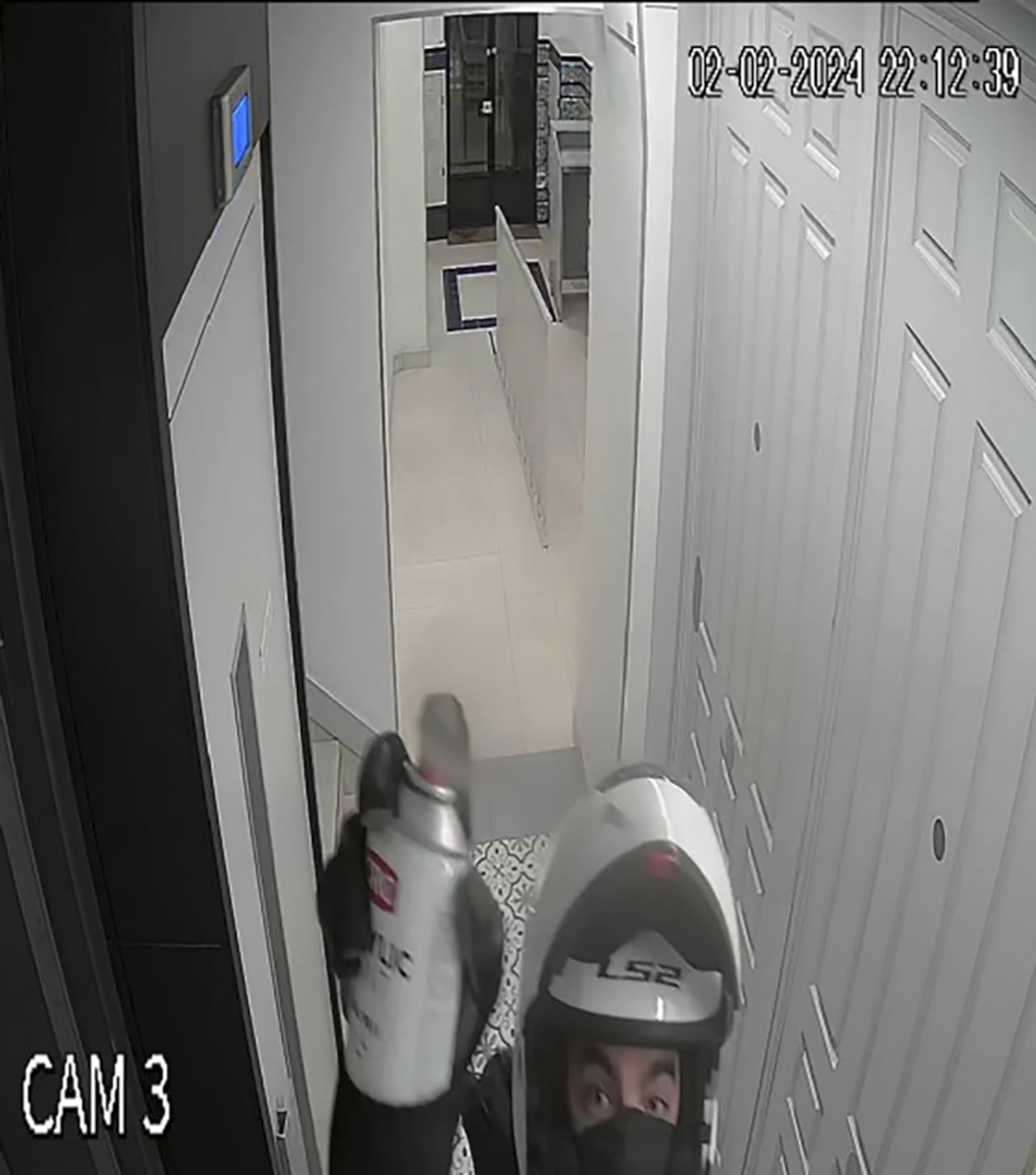 Esta imagen tomada de un vídeo proporcionado por la Fiscalía Federal de Miami muestra a un hombre con un casco de motocicleta pintando con spray la cámara de seguridad del apartamento de Ana Knezevich en Madrid, el 2 de febrero de 2024.