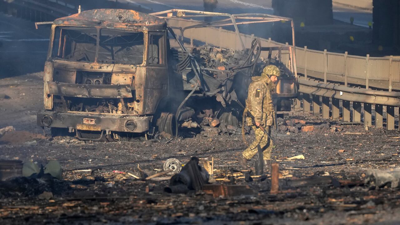 Un soldado ucraniano se desplaza entre los restos de un camión militar incendiado en una calle en Kiev, Ucrania, el sábado 26 de febrero de 2022. (AP Foto/Efrem Lukatsky)