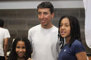 Egan bernal posa con dos niñas que asistieron a la entrega del kit de la competencia Ruta Valle Invencible, que también tuvo un conversatorio.