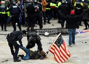 (FILES) In this file photo taken on January 6, 2021, police detain a person as supporters of US President Donald Trump riot outside the US Capitol in Washington, DC. - A day after the Senate acquitted Donald Trump in a historic second impeachment trial, America was weighing how long a shadow the former president, even with a tarnished legacy, will continue to cast -- over his party, and over the country. As much of the world watched, the Senate on February 13, 2021 voted 57-43 to convict Trump of inciting the January 6 assault on the US Capitol. It was a stinging rebuke, with seven Republicans joining all Democrats in the most bipartisan impeachment vote ever, but it fell short of the 67 votes needed for conviction. (Photo by ROBERTO SCHMIDT / AFP)