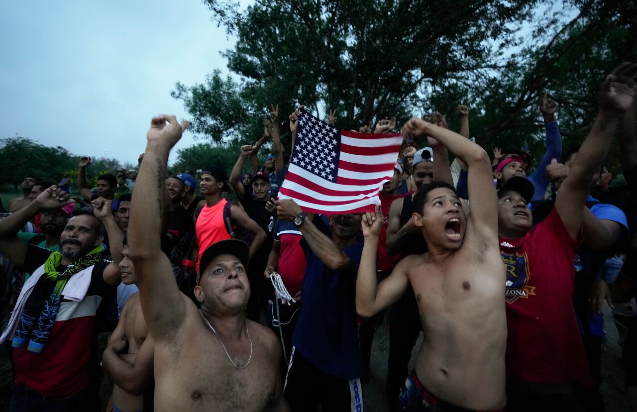 Migrantes venezolanos ondean una bandera estadounidense hacia un helicóptero de televisión que sobrevuela la zona junto al río Bravo (Grande) en Matamoros, México, el viernes 12 de mayo de 2023, un día después de que se retiraron las restricciones al asilo implementadas en la pandemia de coronavirus, conocidas como Título 42. La imagen fue parte de una serie tomada por los fotógrafos de The Associated Press Iván Valencia, Eduardo Verdugo, Félix Márquez, Marco Ugarte, Fernando Llano, Eric Gay, Gregory Bull y Christian Chávez que ganó el Premio Pulitzer 2024 en Fotografía de Reportaje. (AP Foto/Fernando Llano)