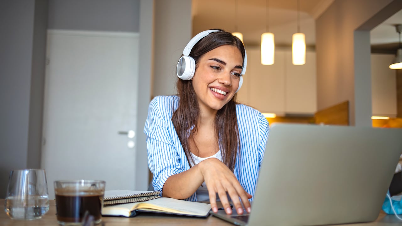 Mujer estudiante toma clases virtuales con audífonos, clases por internet