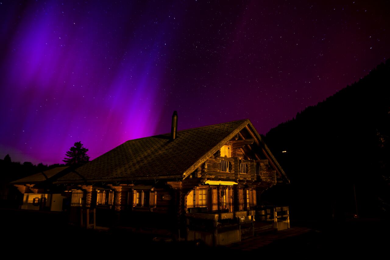 La aurora boreal, o aurora boreal, ilumina el cielo nocturno sobre las montañas
