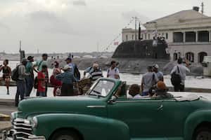 Un conductor pasa en un auto convertible clásico americano mientras la gente mira llegar al submarino de propulsión nuclear “Kazan” a aguas cubanas el miércoles 12 de junio de 2024. El 13 de junio, as autoridades cubanas y rusas permitieron el acceso de los ciudadanos a la fragata rusa “Gorshkov”. (AP Foto/Ariel Ley)