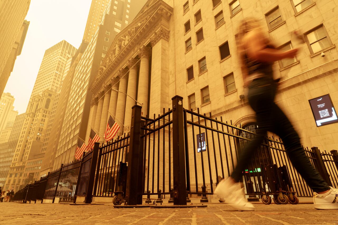 Una transeúnte camina entre el humo y la bruma cerca de la Bolsa de Valores de Nueva York, el miércoles 7 de junio de 2023. (AP Foto/J. David Ake)