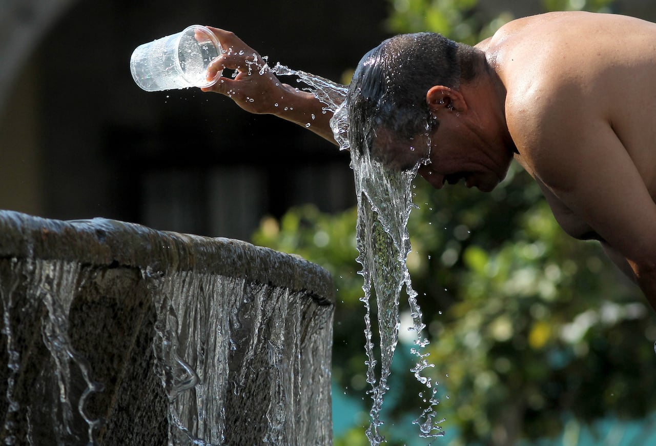 A man cools himself down with water from a water fountain during one of the hottest days of the third heat wave in Guadalajara, Jalisco state, Mexico, on June 12, 2023. (Photo by ULISES RUIZ / AFP)