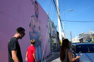Un grupo de personas caminan frente a un mural del astro argentino del fútbol Lionel Messi hecho por Arlex Campos en Miami, el domingo 9 de julio de 2023 (AP Foto/Lynne Sladky)