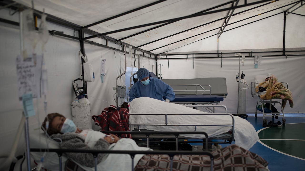 Un trabajador de la salud atiende a un paciente con COVID-19 en una carpa instalada en la cancha de fútbol del Hospital Samaritana, en Bogotá. (Foto AP / Ivan Valencia)