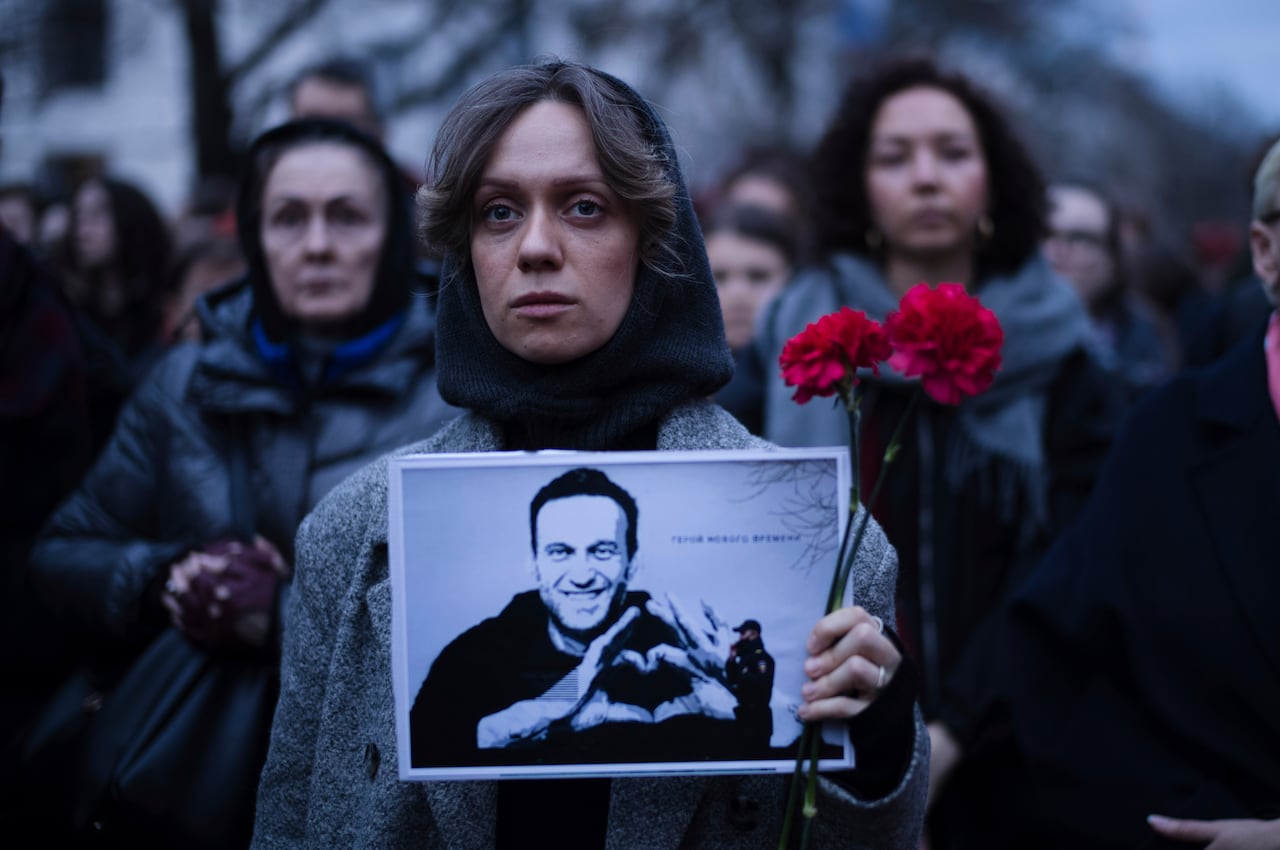 Una mujer sostiene flores y un retrato del líder opositor Alexei Navalny durante una protesta frente a la embajada rusa en Berlín, Alemania, el viernes 16 de febrero de 2024.