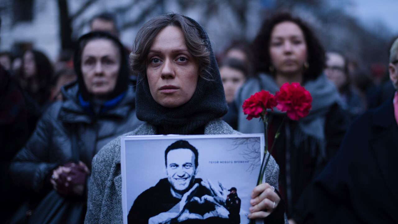 Una mujer sostiene flores y un retrato del líder opositor Alexei Navalny durante una protesta frente a la embajada rusa en Berlín, Alemania, el viernes 16 de febrero de 2024.