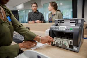 Bank teller using cash counting machine in bank branch