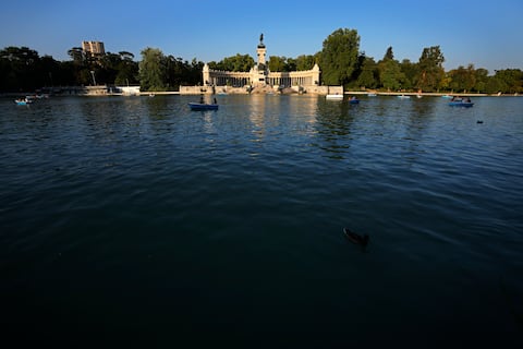 Algunas personas reman en el lago frente al monumento al rey Alfonso XII el viernes 23 de julio de 2021, en el Parque del Retiro, en Madrid, España. (AP Foto/Paul White)