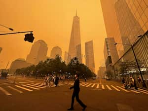 Transeúntes caminan frente al One World Trade Center en medio de la humareda por los incendios forestales de Canadá, el miércoles 7 de junio de 2023, en Nueva York. (AP Foto/Julie Jacobson)