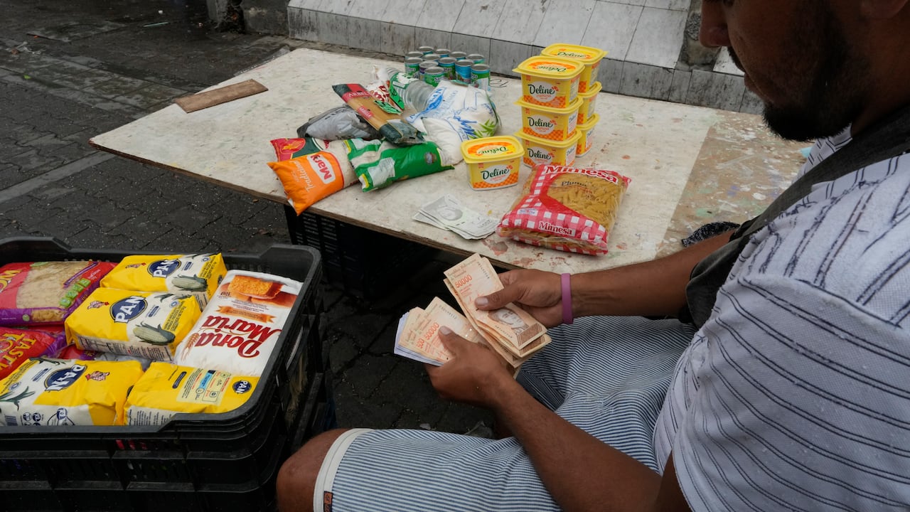 Un hombre cuenta billetes en Caracas, Venezuela. (AP Foto/Ariana Cubillos)