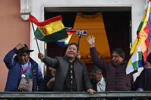 Bolivian President Luis Arce waves a Bolivian flag at the balcony of the Government Palace in La Paz on June 26, 2024. Bolivian President Luis Arce on Wednesday slammed an attempted "coup d'etat" after soldiers and tanks deployed outside government buildings and tried to knock down a door of the presidential palace, before pulling back. (Photo by AIZAR RALDES / AFP)