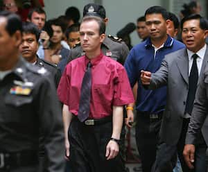 BANGKOK, THAILAND - AUGUST 20:  American John Mark Karr (C) is led by Thai police from the immigration detention facility to the airport to depart for the U.S. August 20, 2006 in Bangkok, Thailand. Karr, 41, is a suspect in the 1996 murder of six-year-old JonBenet Ramsey in Boulder, Colorado. According to Thai police, Karr has confessed to the crime, saying Ramsey's death was not intentional.  (Photo by Paula Bronstein/Getty Images)